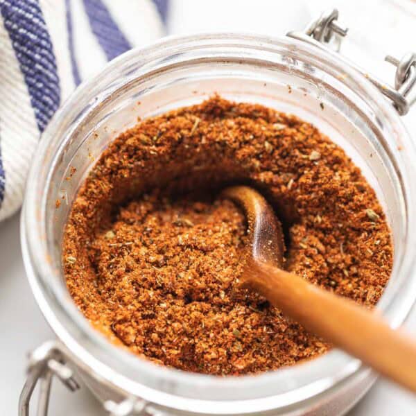 Homemade Low Fodmap Fajita Seasoning mixed in a small storage jar with a wooden spoon.