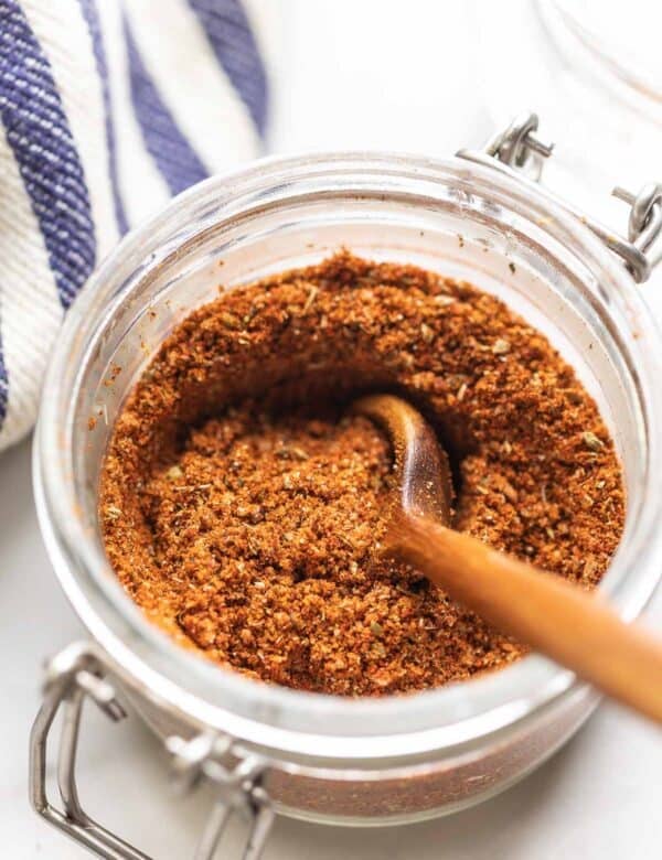 Homemade Low Fodmap Fajita Seasoning mixed in a small storage jar with a wooden spoon.