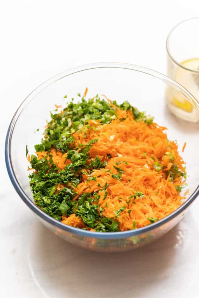 Grated carrots, chopped parsley and spring onions in a large salad bowl.