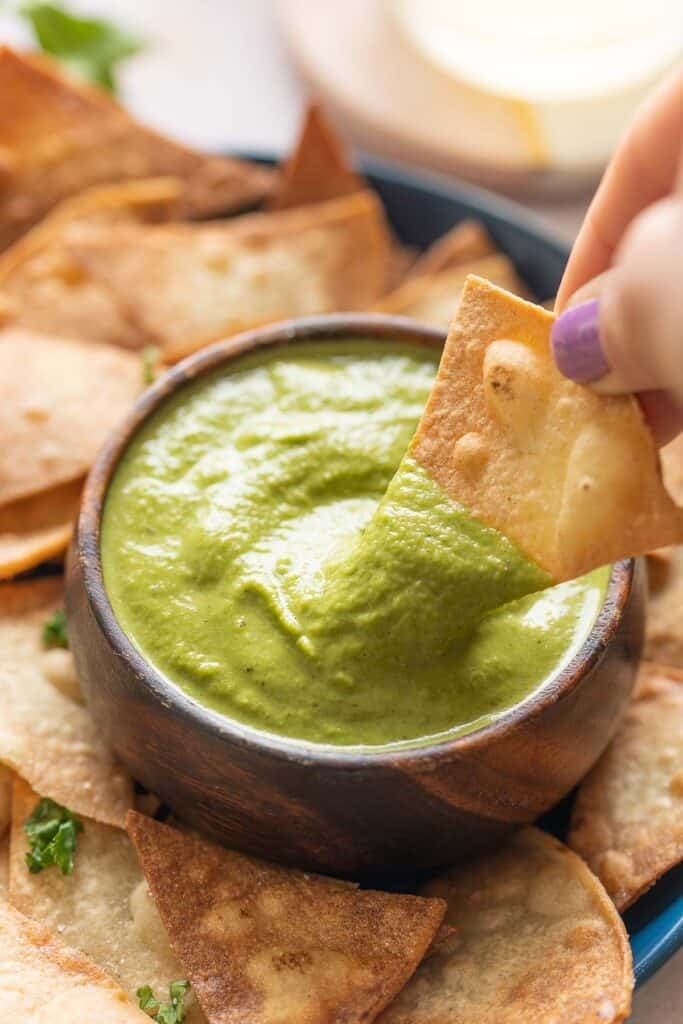 A tortilla chip dipping into a bowl of homemade jalapeño zucchini salsa.