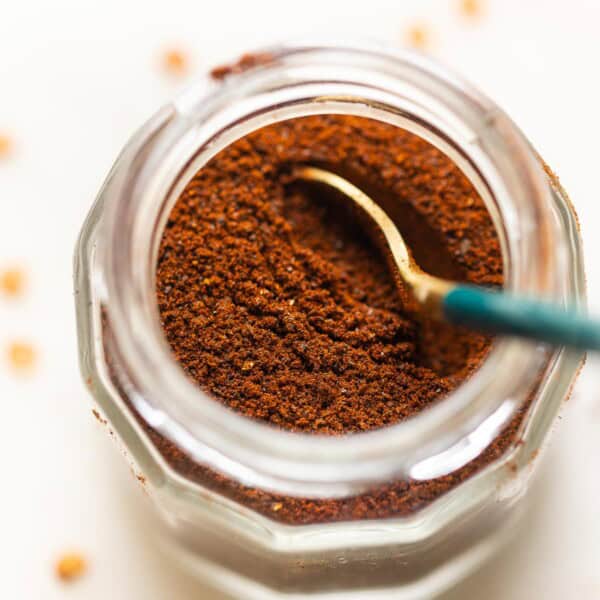 Homemade Ancho Chili Powder in a spice jar with a spoon.