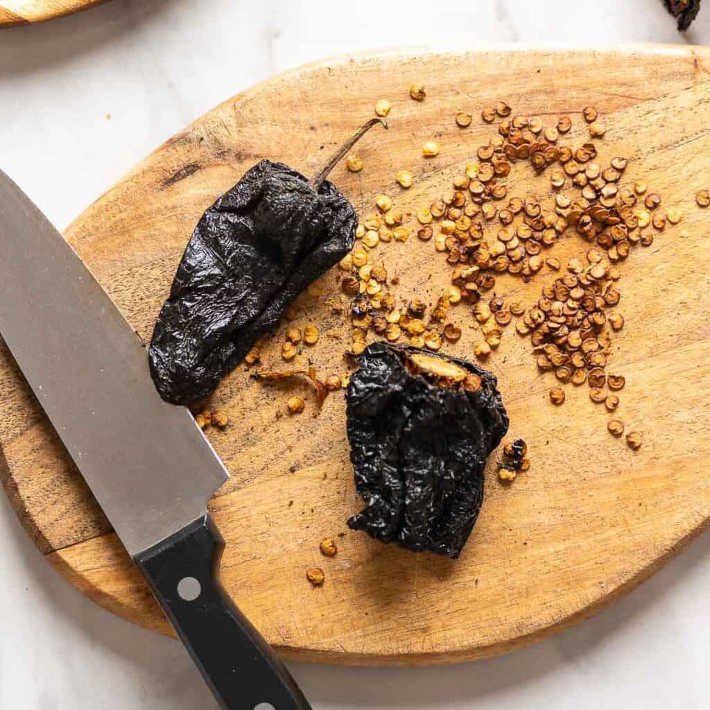 Whole, dried ancho chiles cut up on a cutting board with the stems and seeds removed.