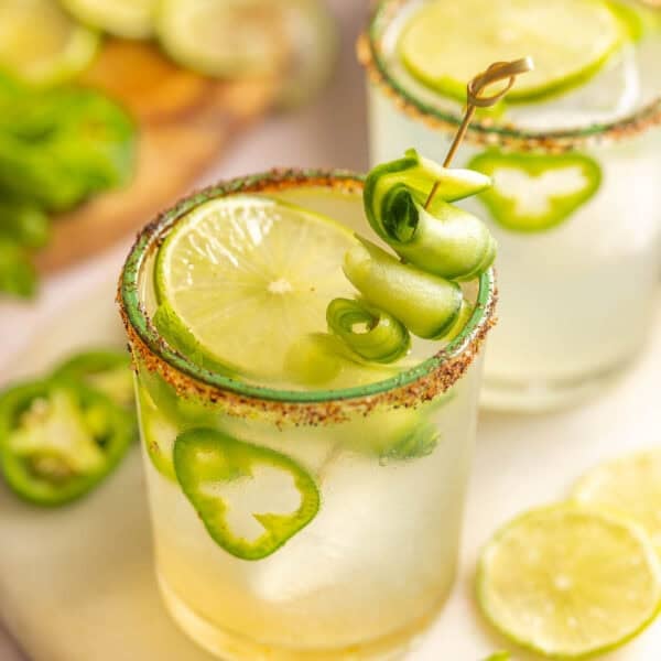 Jalapeño Cucumber Margaritas in a couple of salt and chili rimmed glasses garnished with cucumber slices, jalapeno slices and fresh mint leaves inside