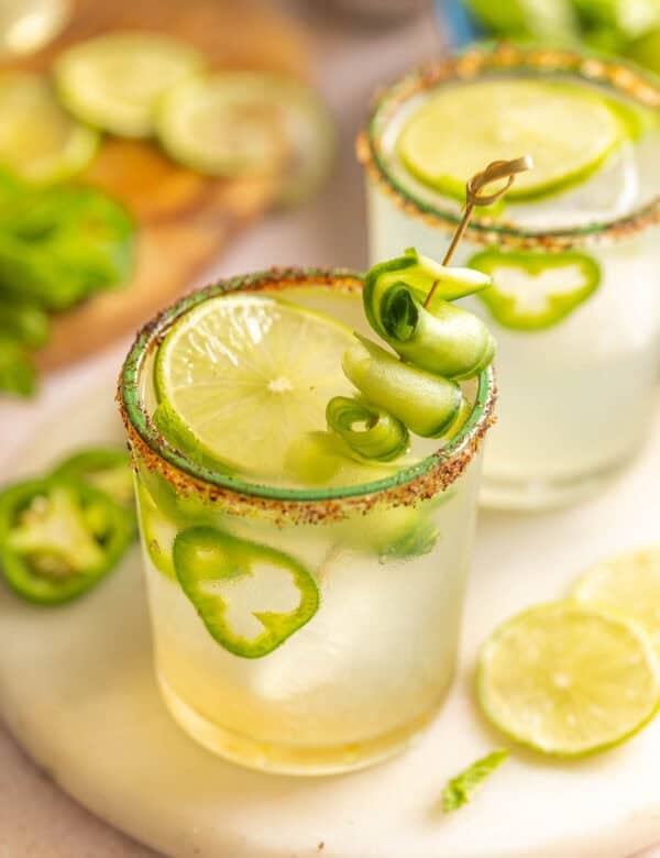 Jalapeño Cucumber Margaritas in a couple of salt and chili rimmed glasses garnished with cucumber slices, jalapeno slices and fresh mint leaves inside