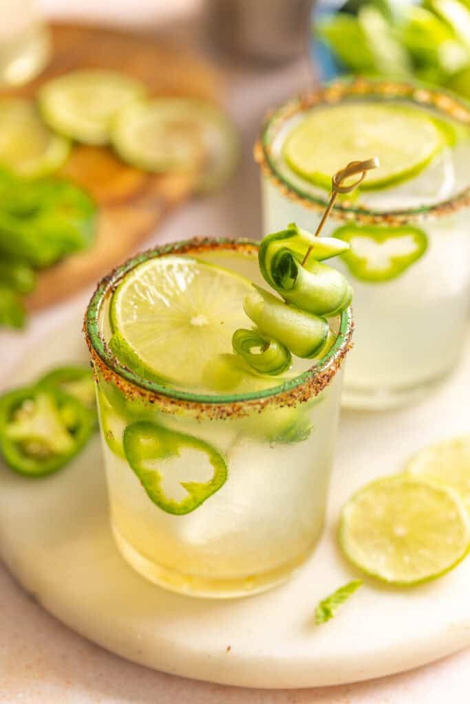 Jalapeño Cucumber Margaritas in a couple of salt and chili rimmed glasses garnished with cucumber slices, jalapeno slices and fresh mint leaves inside