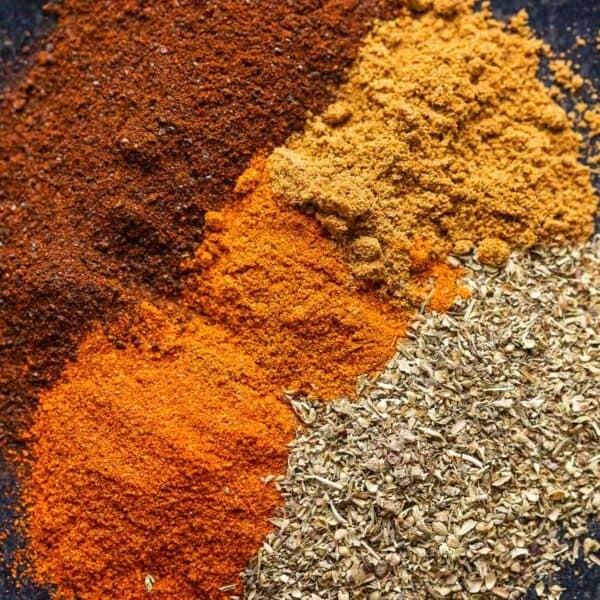 Low FODMAP Chili Spices on a plate: ancho chili powder, oregano, paprika, cayenne and cumin