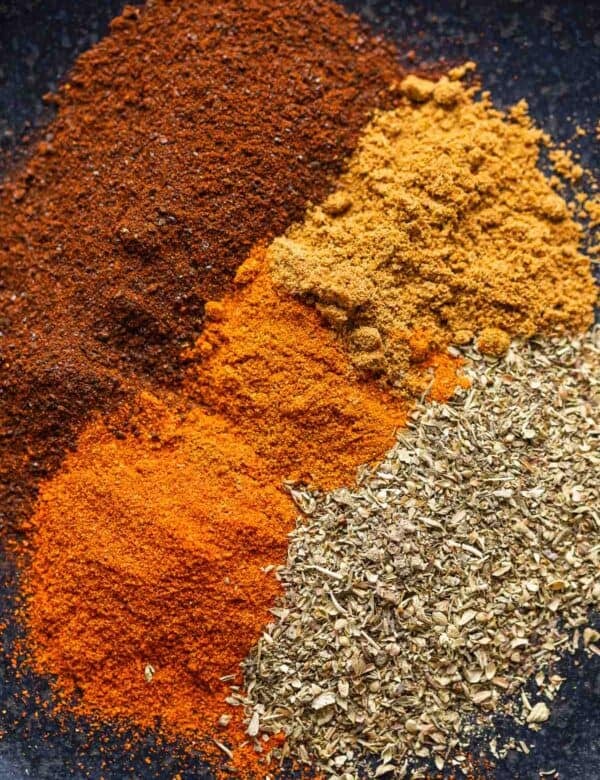 Low FODMAP Chili Spices on a plate: ancho chili powder, oregano, paprika, cayenne and cumin