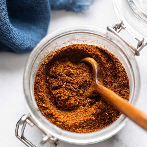 Homemade Low FODMAP Chili Powder mixed together in a small storage jar with a wooden spoon.