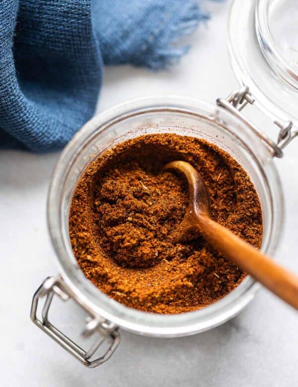 Homemade Low FODMAP Chili Powder mixed together in a small storage jar with a wooden spoon.