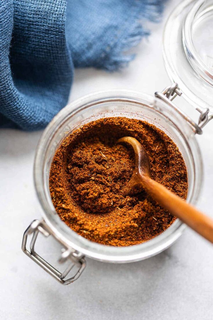 Homemade Low FODMAP Chili Powder mixed together in a small storage jar with a wooden spoon.