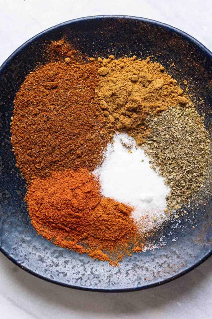 Low FODMAP Taco Spices on a plate: chili powder, paprika, oregano, cumin, salt and cayenne.
