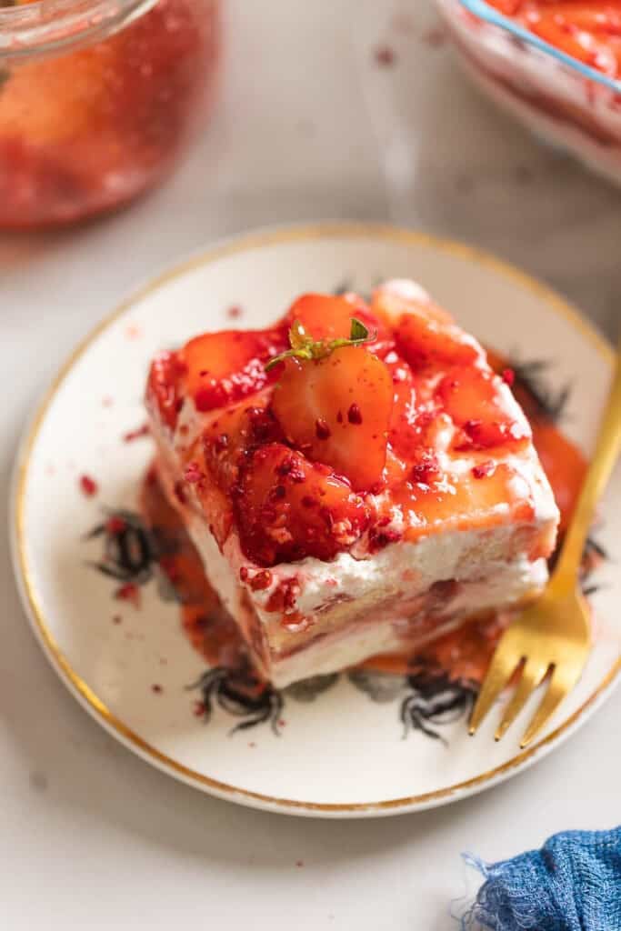 A slice of a Strawberry shortcake tiramisu on a cake plate with a fork.