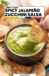 Jalapeño Zucchini Salsa (Guacachile) pinterest marketing image from A Saucy Kitchen: paleo + vegan. A tortilla chip dipping in a bowl of jalapeño zucchini salsa.