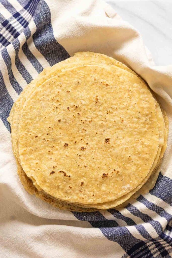 A stack of homemade gluten free flour tortillas in a kitchen towel.