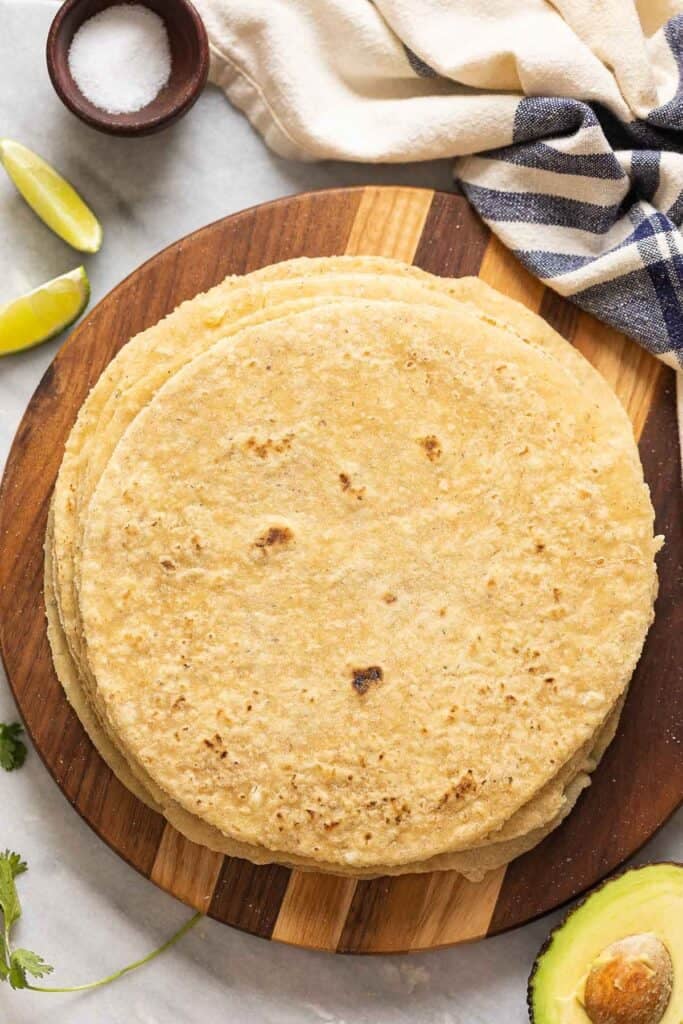 A stack of homemade gluten free flour tortillas on a wooden serving board.