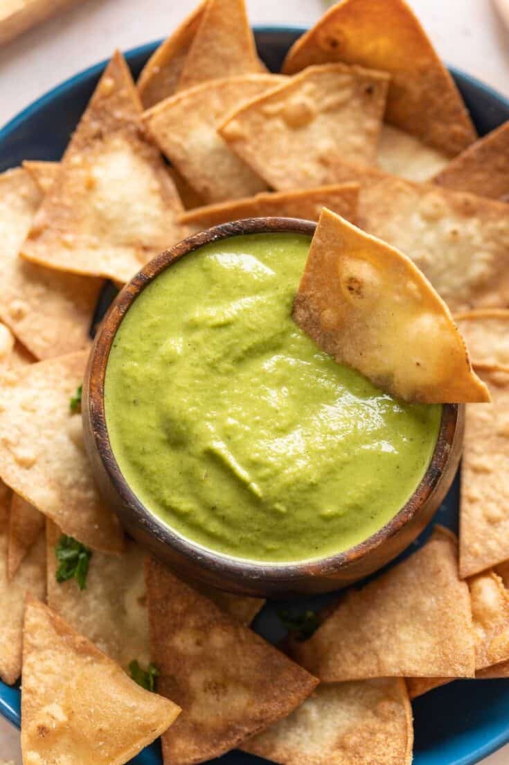 Jalapeño Zucchini Salsa in a dip bowl on a plate with tortilla chips and a tortilla chip in the dip