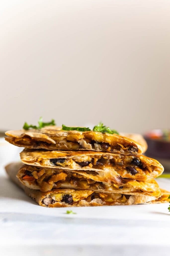 A small stack of four Sweet Potato & Black Bean Quesadillas with fresh chopped cilantro on top.