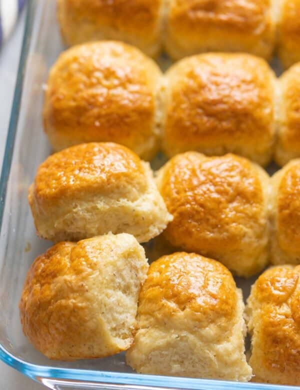 Gluten free dinner rolls in a 9x13-inch glass baking dish - some of the bread rolls are positioned to show the soft middles.