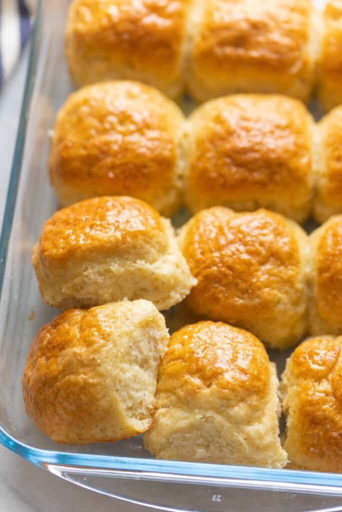 Gluten free dinner rolls in a 9x13-inch glass baking dish - some of the bread rolls are positioned to show the soft middles.