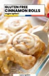 Gluten Free Cinnamon Rolls: vegan option from A Saucy Kitchen: a cinnamon roll covered in a cream cheese glaze held up on a spatula.