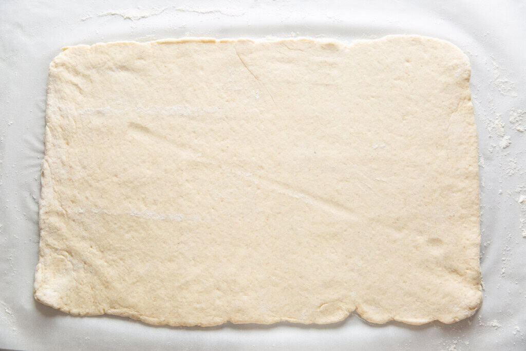 Gluten free cinnamon roll dough rolled out in a big in a big rectangle.