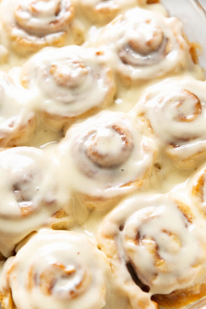 An up close perspective of homemade gluten free cinnamon rolls covered in a cream cheese frosting.