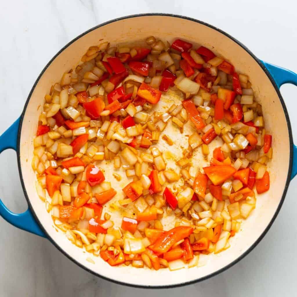 A casserole dish full of sautéd onion, garlic & bell pepper.