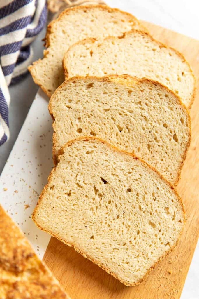 Four slices of Gluten Free Sandwich Bread on a wooden cutting board.