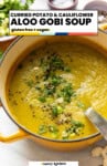 Pinterest marketing image from A Saucy Kitchen: Curried Potato & Cauliflower Aloo Gobi Soup; gluten free + vegan; A soup pot full of soup topped with fresh spring onion, herbs and nigella seeds.