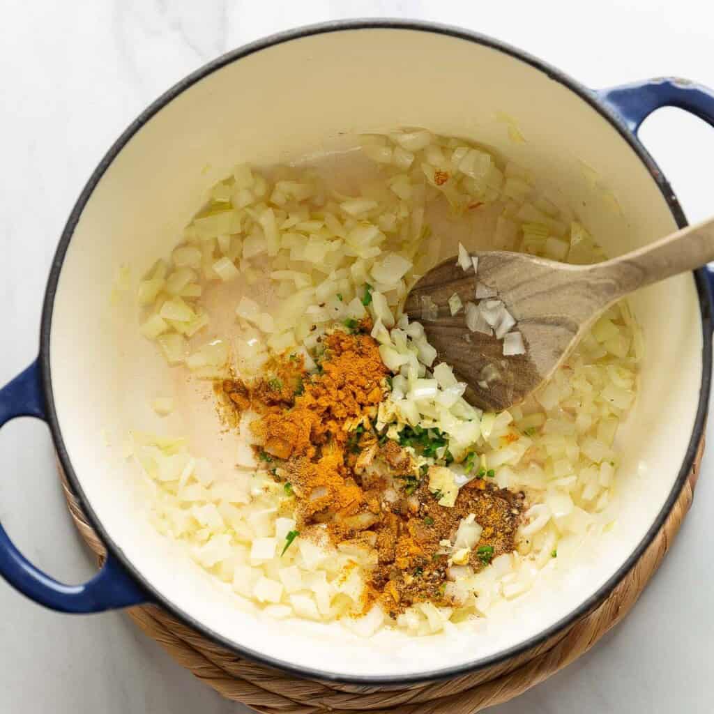 A large dutch oven pot sautéd onion, fresh ginger, green chilies, turmeric powder, coriander powder, cumin powder and black pepper.
