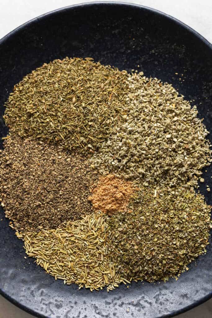 Unmixed Homemade Poultry Seasoning spices on a plate sage, thyme, marjoram, rosemary, black pepper and nutmeg