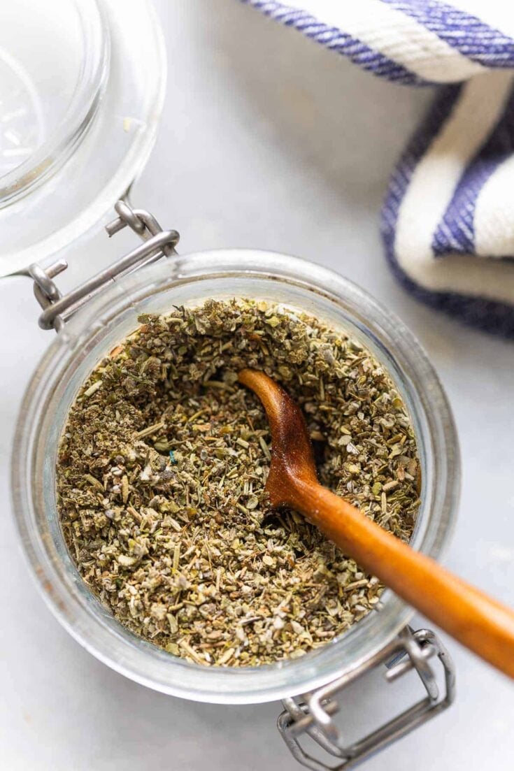 Homemade Poultry Seasoning mixed together in a small jar with a spoon inside.