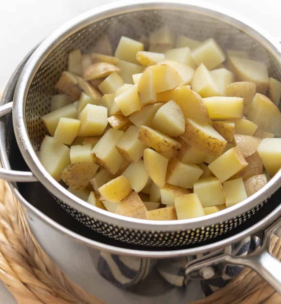 Par boiled potatoes in a steaming basket over a hot pot so the potatoes can steam dry from the residual heat of the pan.