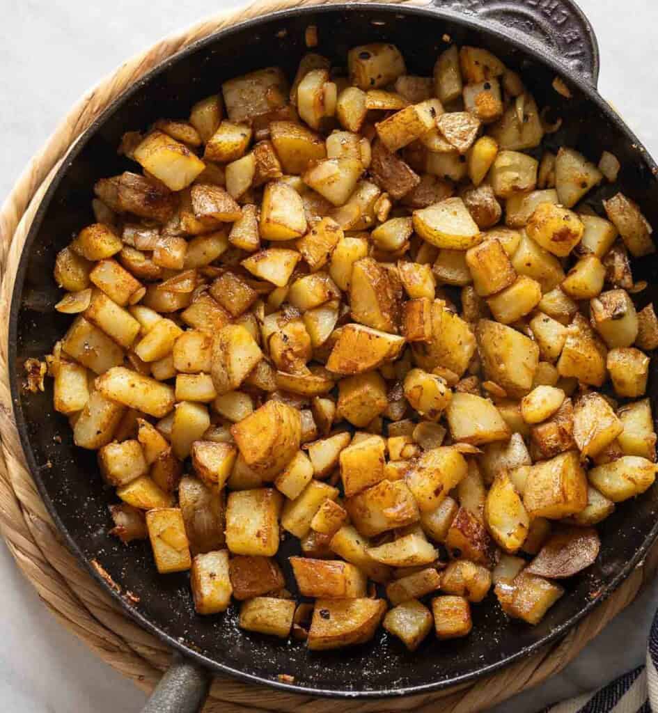 Breakfast Potatoes made in a cast iron skillet mixed with sautéd onion.