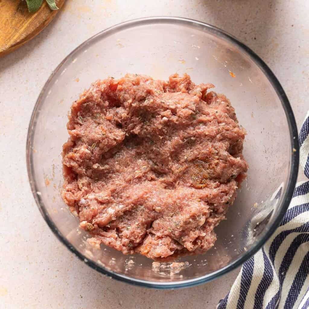 Raw turkey maple breakfast sausage ingredients mixed together in a bowl to make the sausage patties.