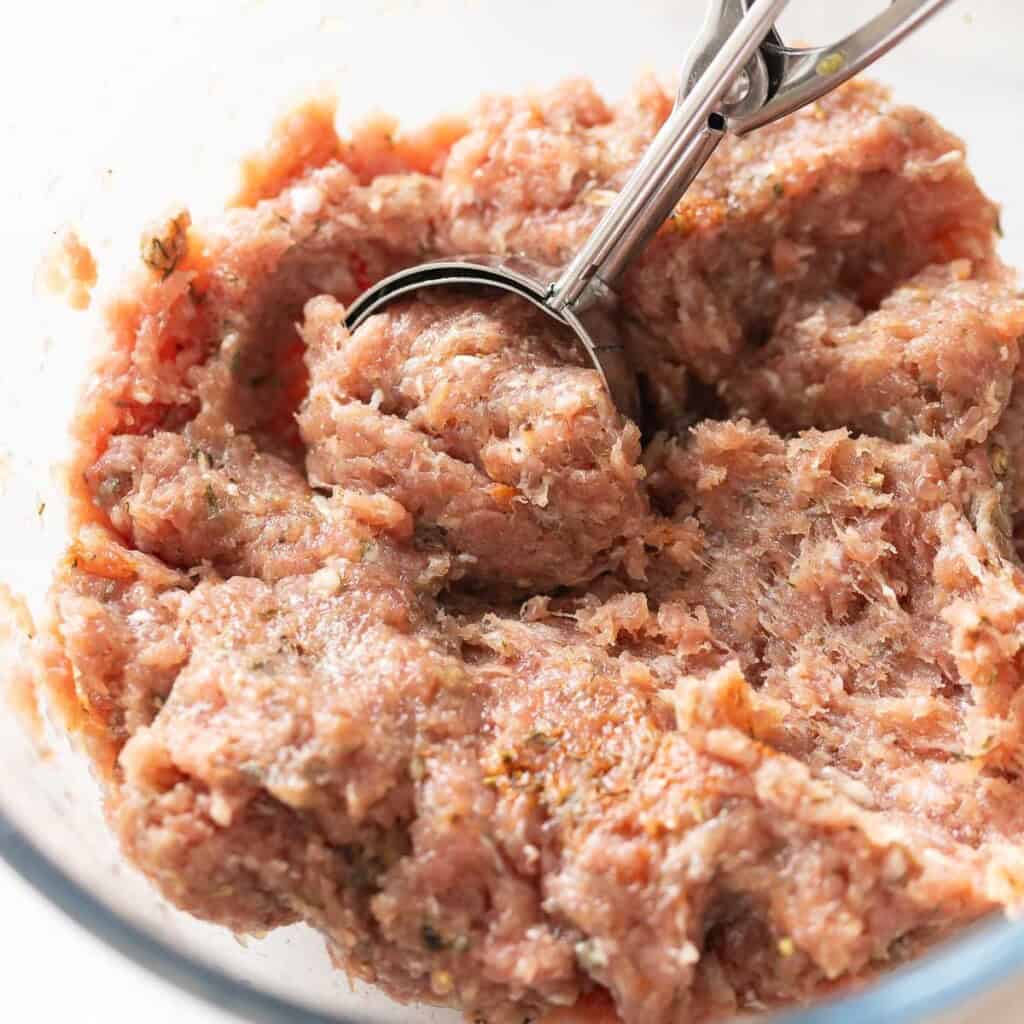 Turkey Maple Breakfast Sausage mince mixed together in a bowl with a cookie scoop scooping out a portion of the meat.