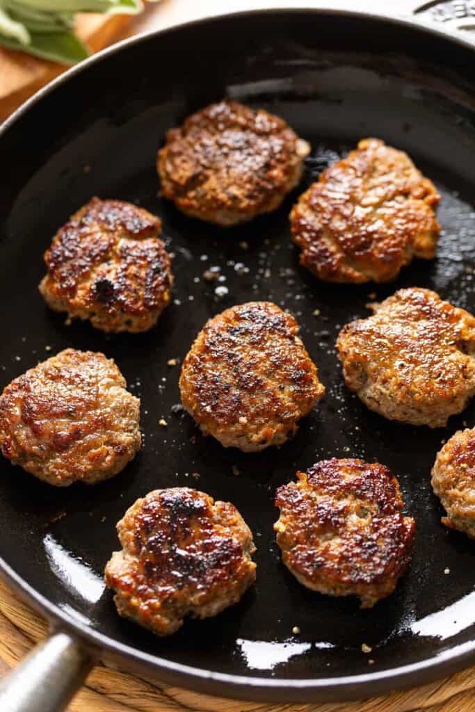 Nine Turkey Maple Breakfast Sausage Patties on a cast iron skillet.