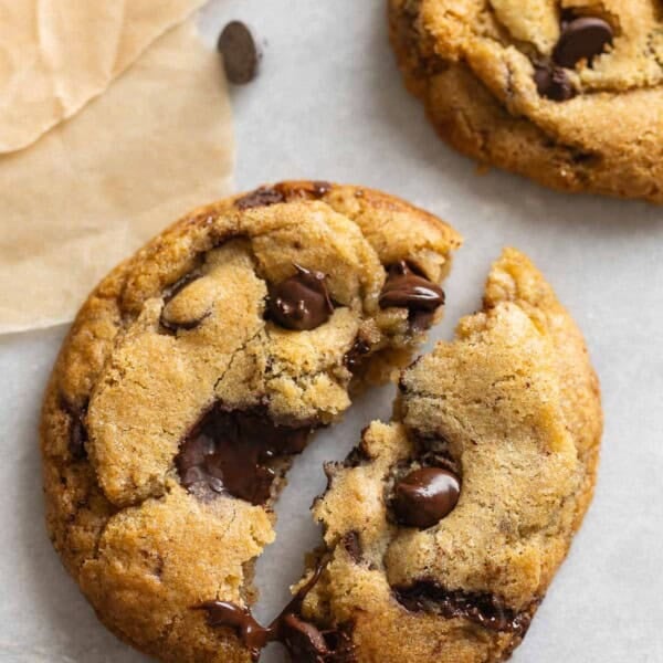 A gluten free brown butter chocolate chip cookie torn into 2 halves with melted chocolate
