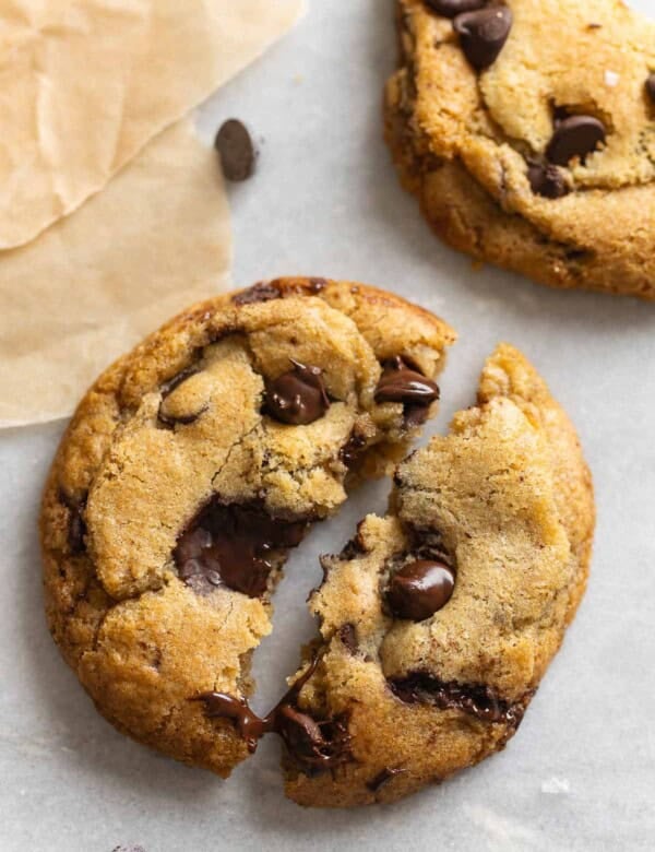 A gluten free brown butter chocolate chip cookie torn into 2 halves with melted chocolate