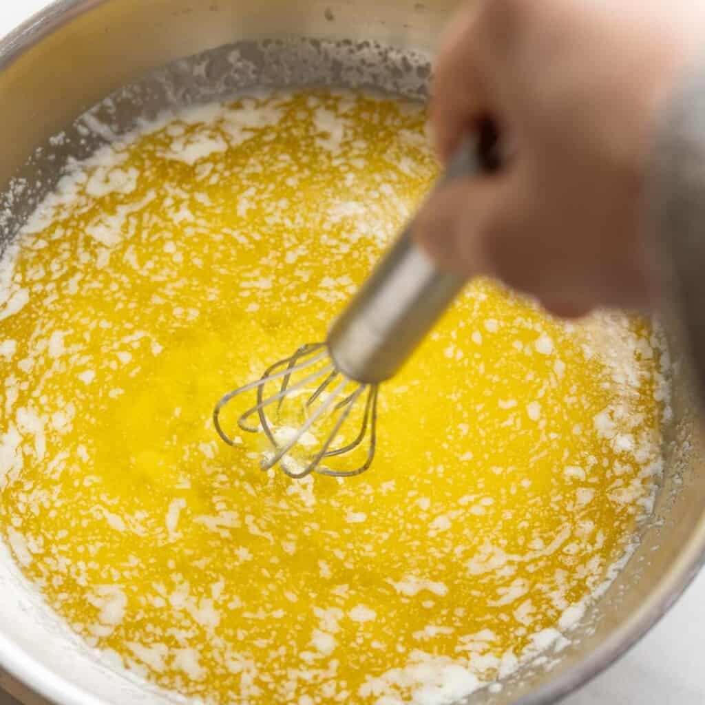 Melted butte whisking in a pan to make brown butter.