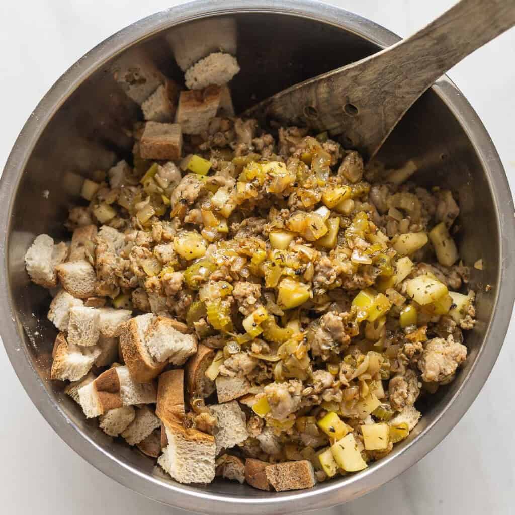 A large mixing bowl full of toasted gluten free bread and sausage stuffing mixture