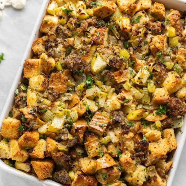 Gluten Free Stuffing with Sausage & Apple in a casserole dish with fresh chopped parsley on top.
