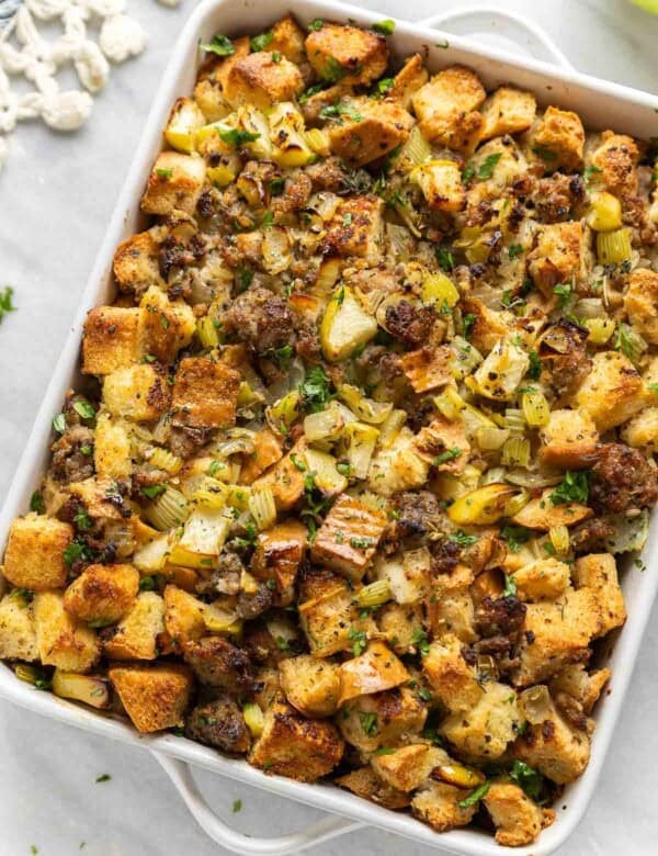 Gluten Free Stuffing with Sausage & Apple in a casserole dish with fresh chopped parsley on top.