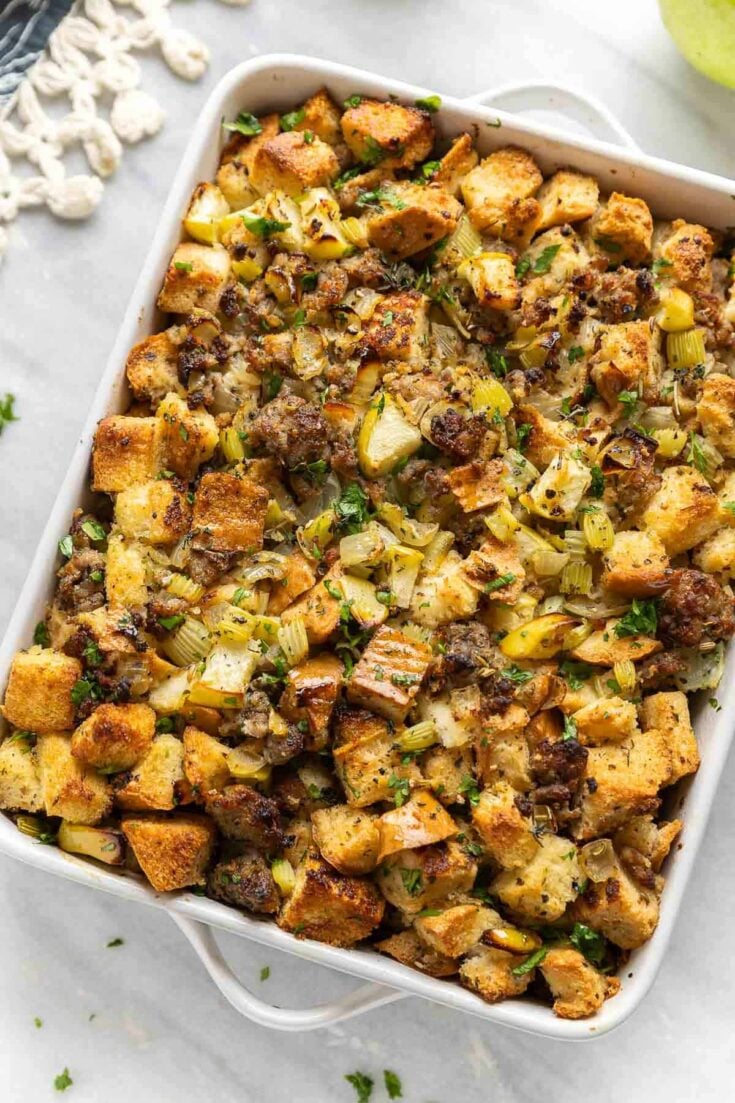 Gluten Free Stuffing with Sausage & Apple in a casserole dish with fresh chopped parsley on top.