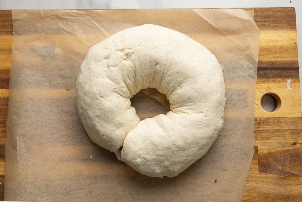 Gluten free pizza dough filled with sausage and cheese rolled up into a log then shaped into a donut-like shape with the ends pinched together.