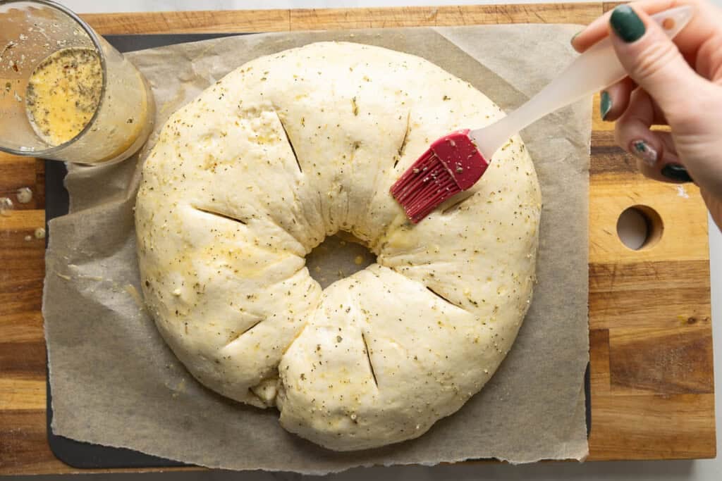 Gluten free sausage bread before baking getting brushed with an egg wash made with milk, italian seasoning & parmesan.