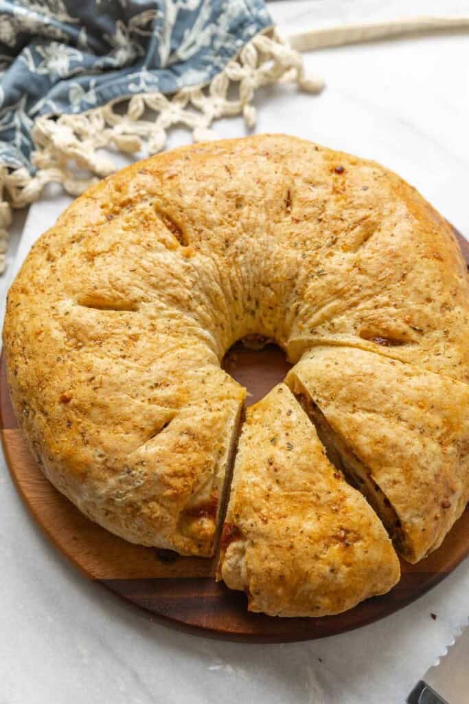 Gluten free sausage bread cut into slices on a wooden cutting board.