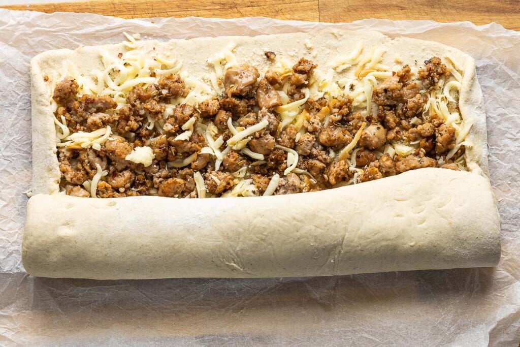 Gluten free dough filled with cheese and sausage and rolled up in a log shape.