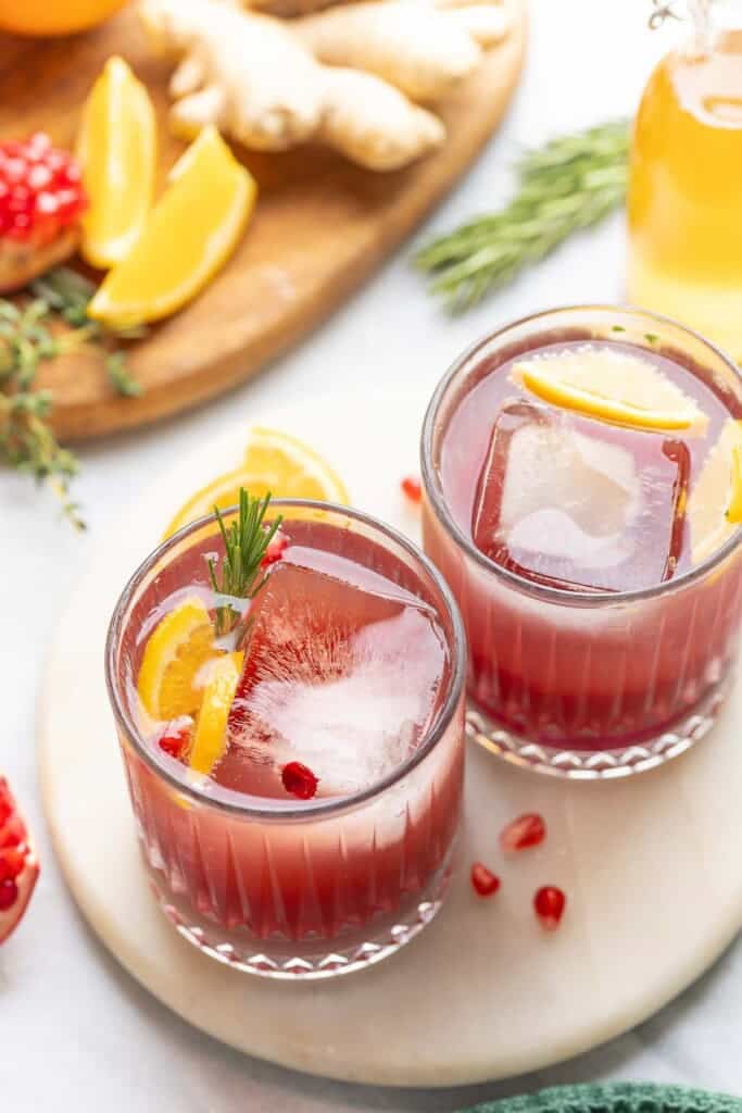 Herby Citrus Pomegranate Mocktails garnished with fresh rosemary, orange slices and pomegranate arils