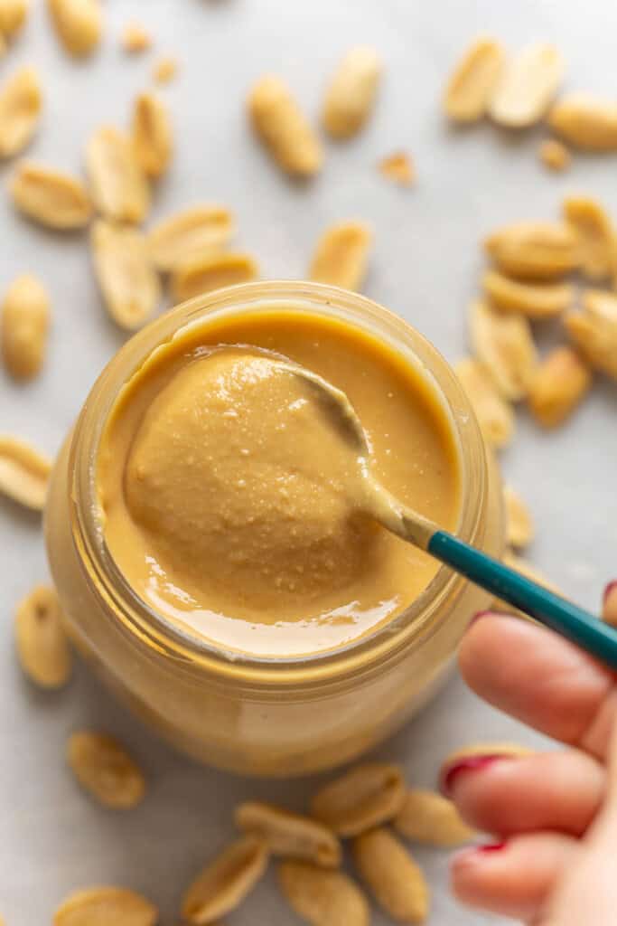 A spoonful of homemade peanut butter in storage jar